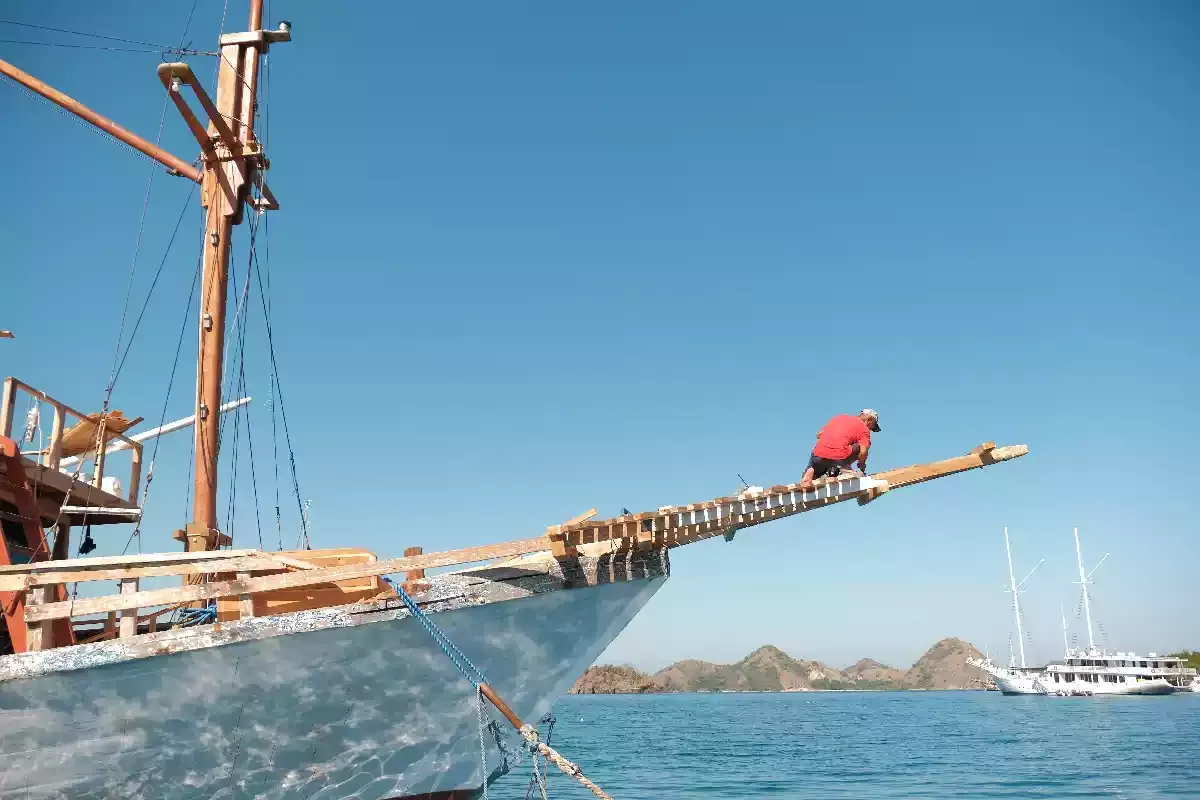Shipwright working on the bowsprit of a phinisi alongside